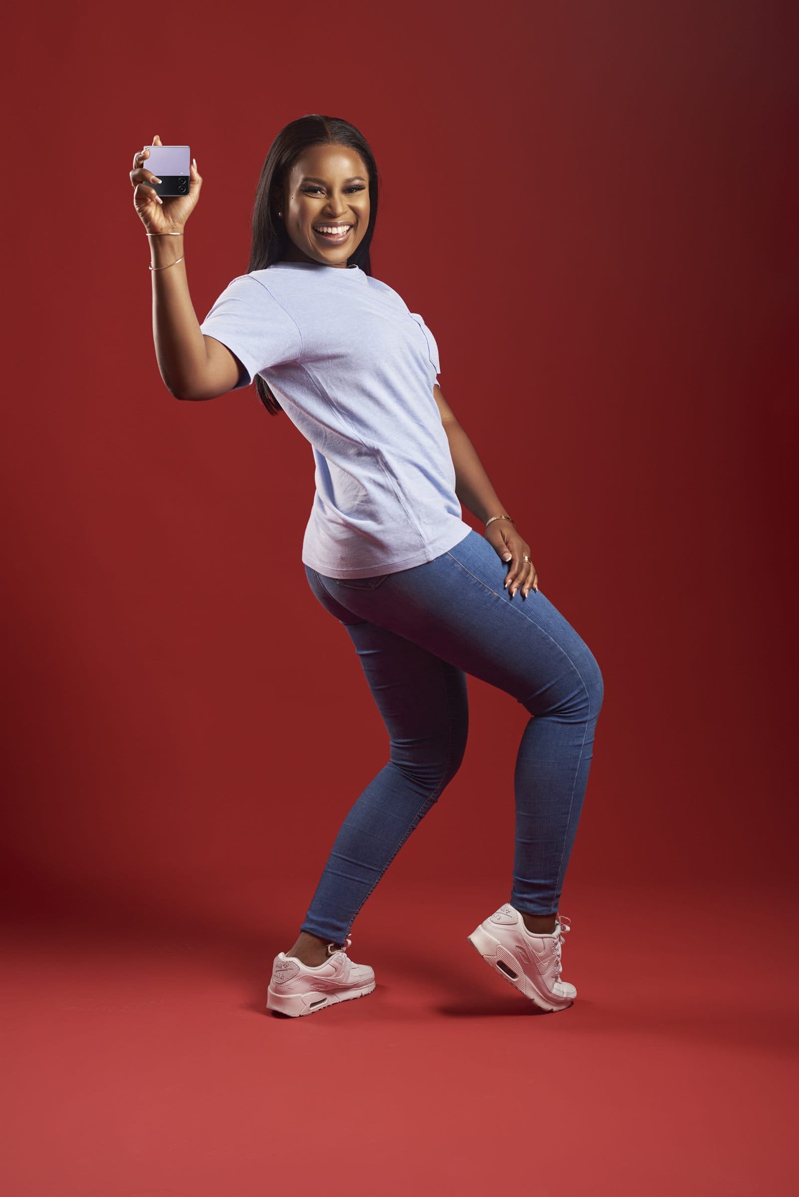 Studio portrait against a red backdrop, phone held overhead