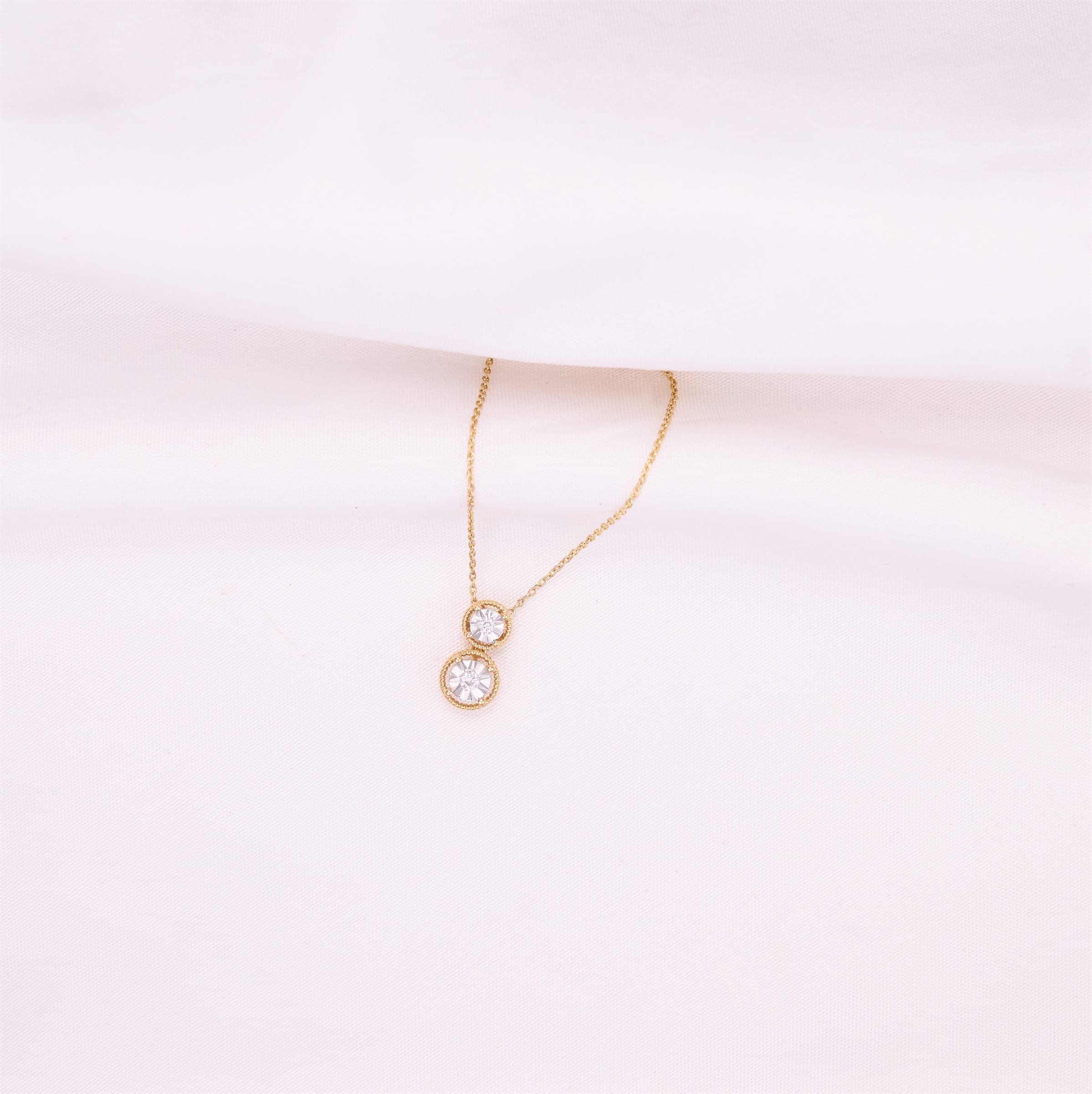 Rose gold pendant with a single stone on soft white fabric