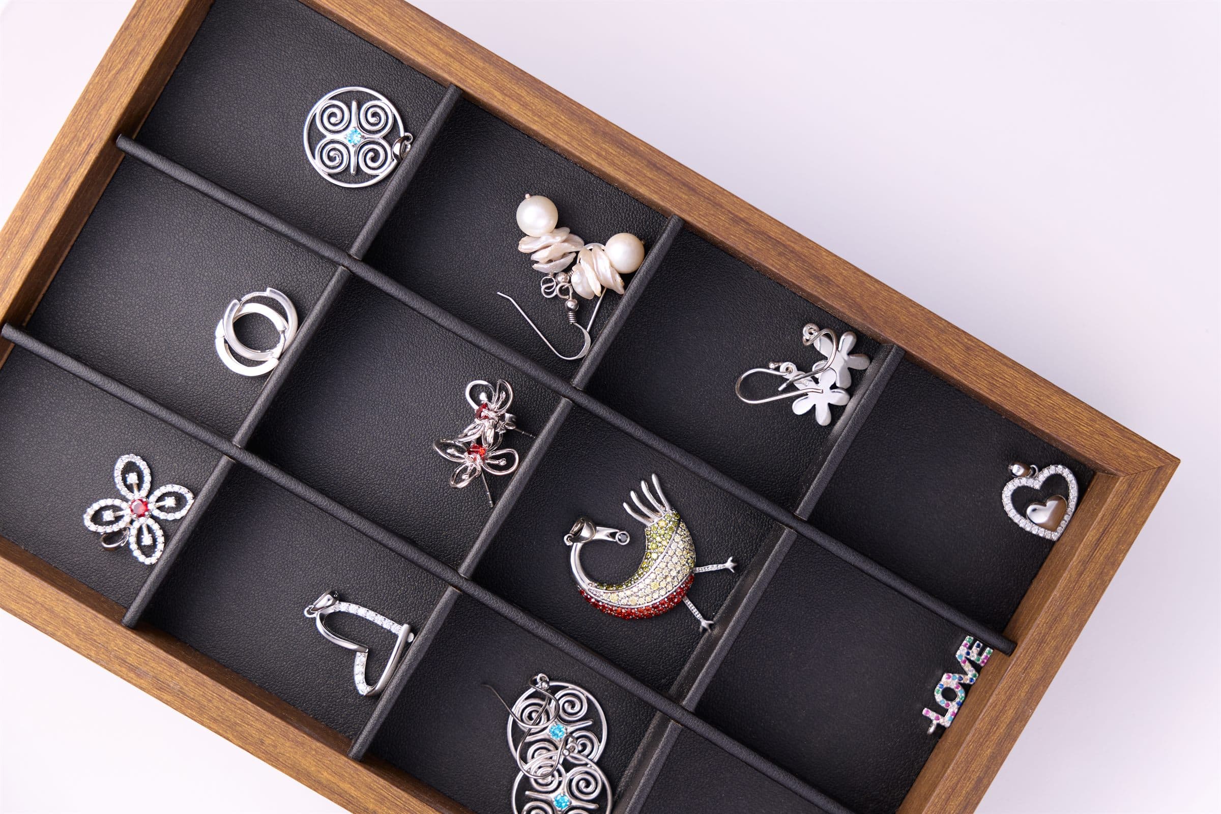 Tray of earrings and pendants laid out in a wooden case