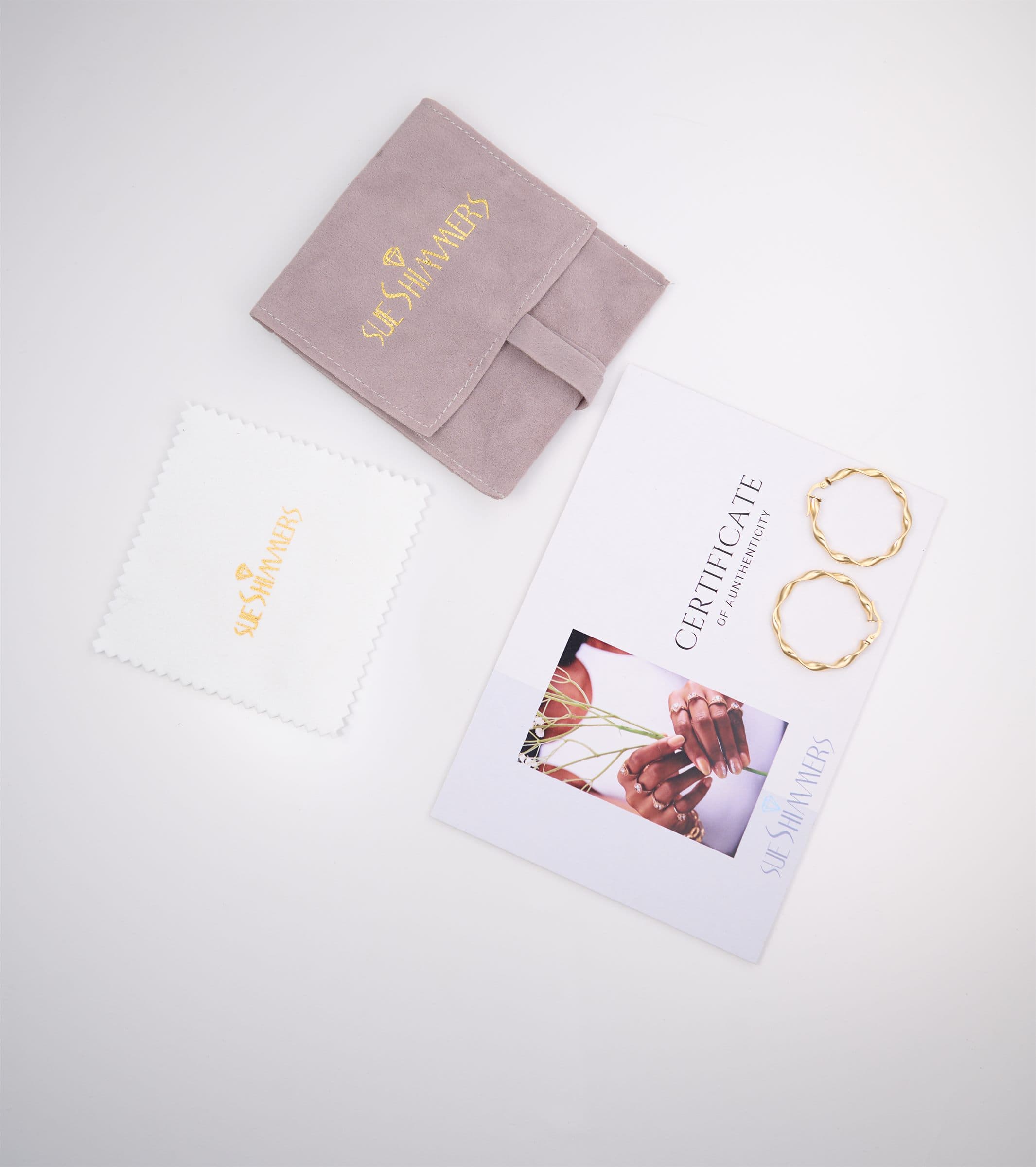 Jewelry pouch, certificate card and gold hoop earrings, flat lay
