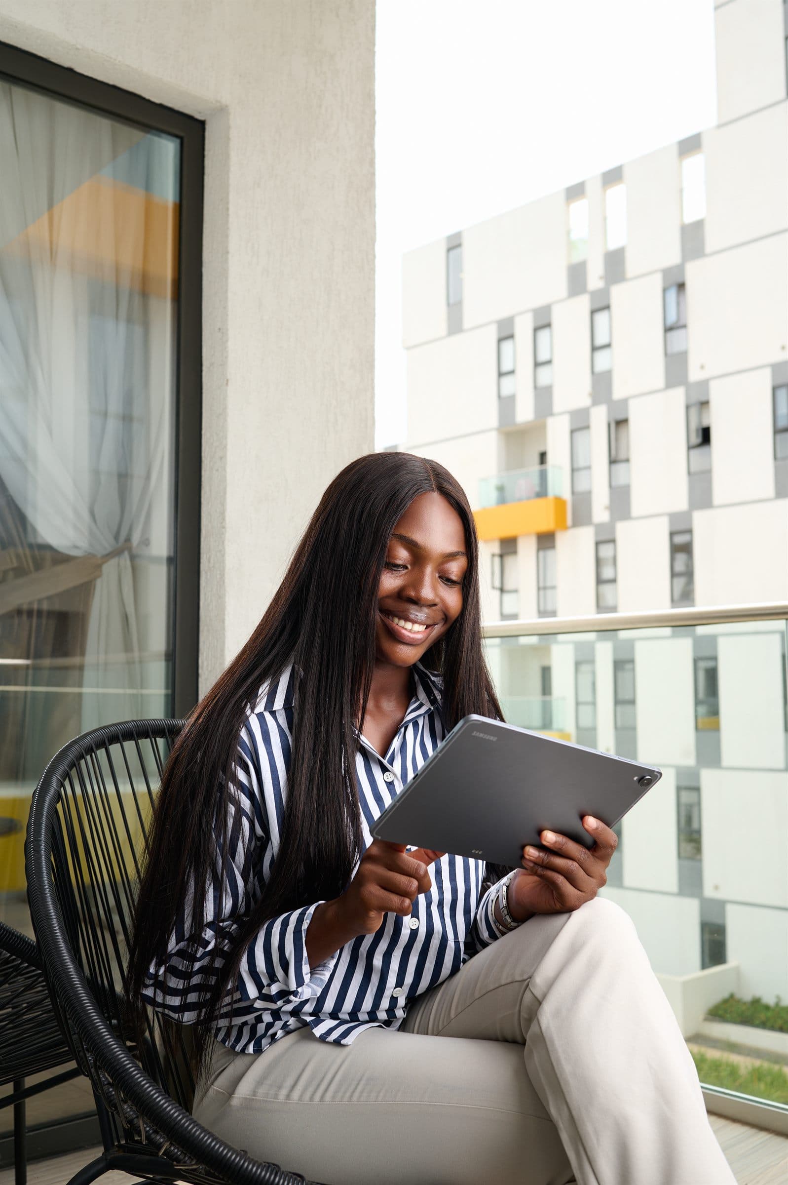Woman reading a tablet on a sunlit balcony