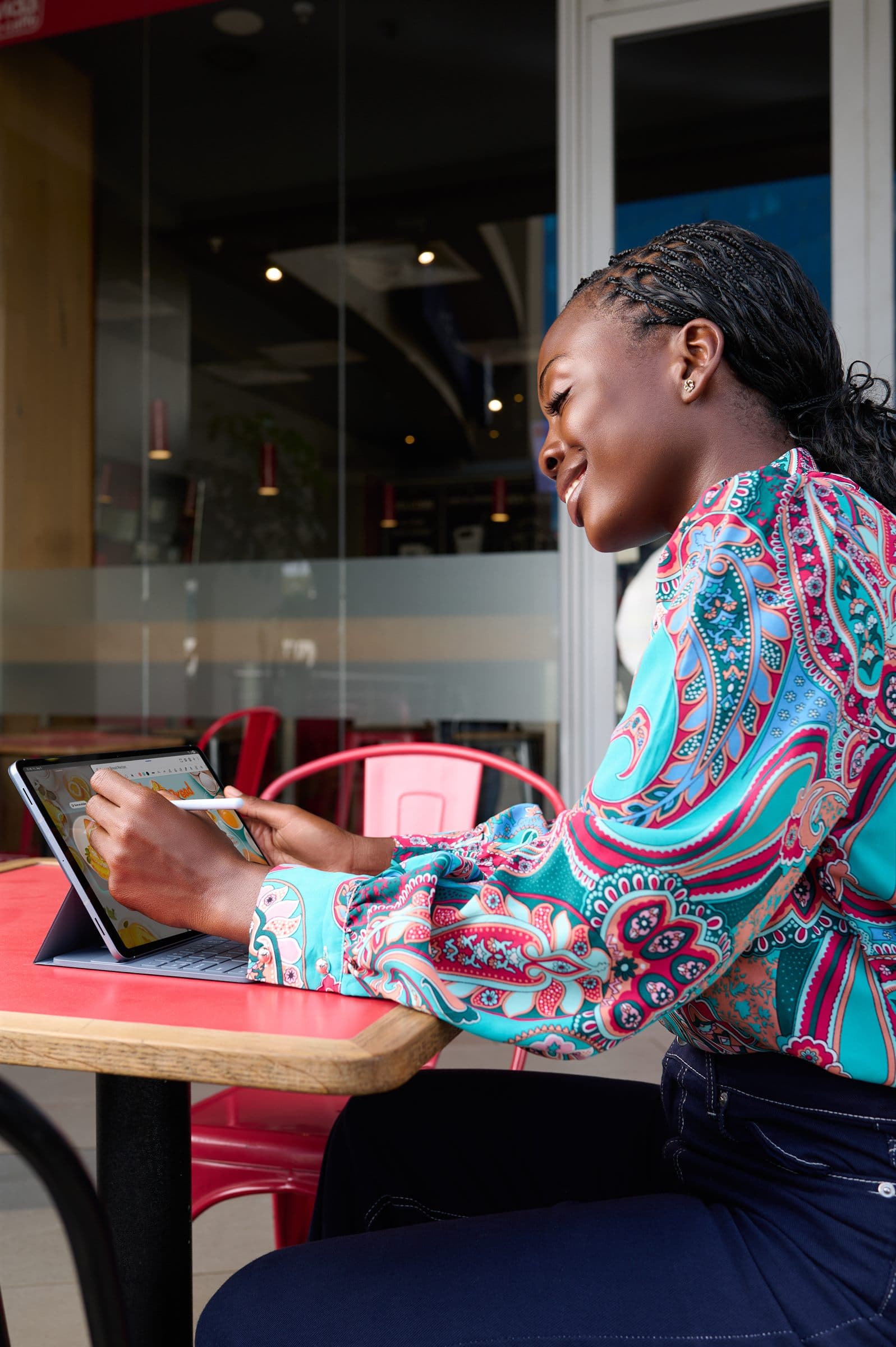 Woman working on a tablet at a cafe window