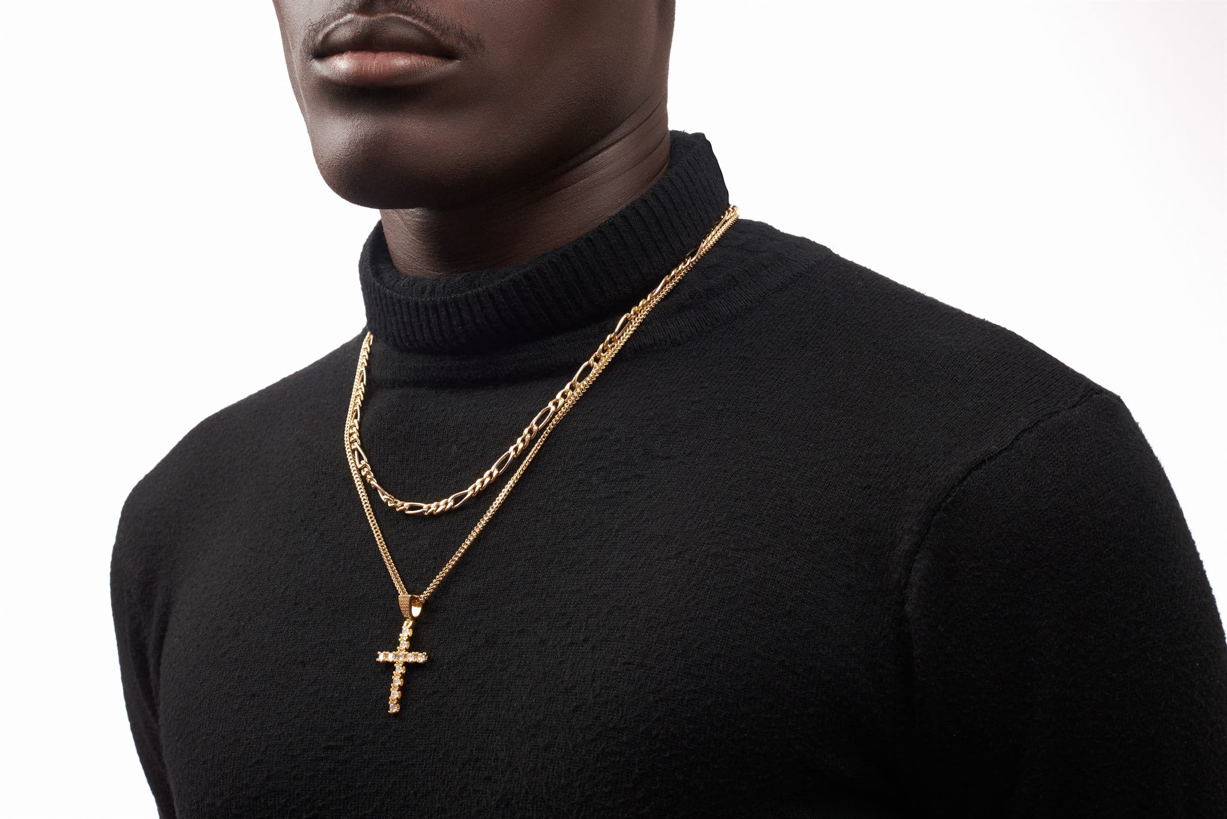 Layered chains with a cross pendant over a black turtleneck