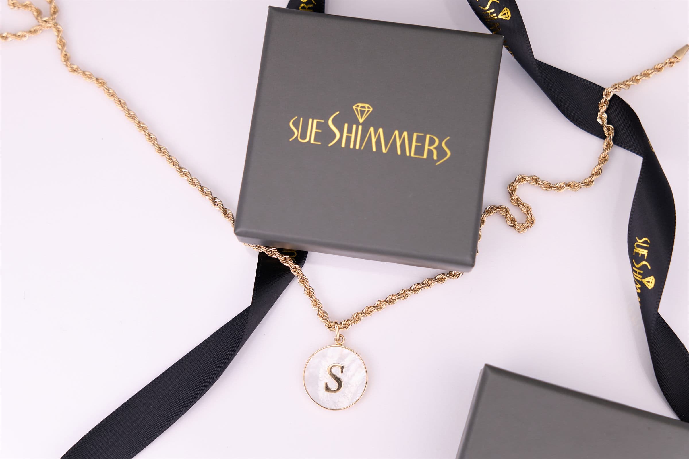 Sue Shimmers gift box with a monogram pendant necklace and black ribbon